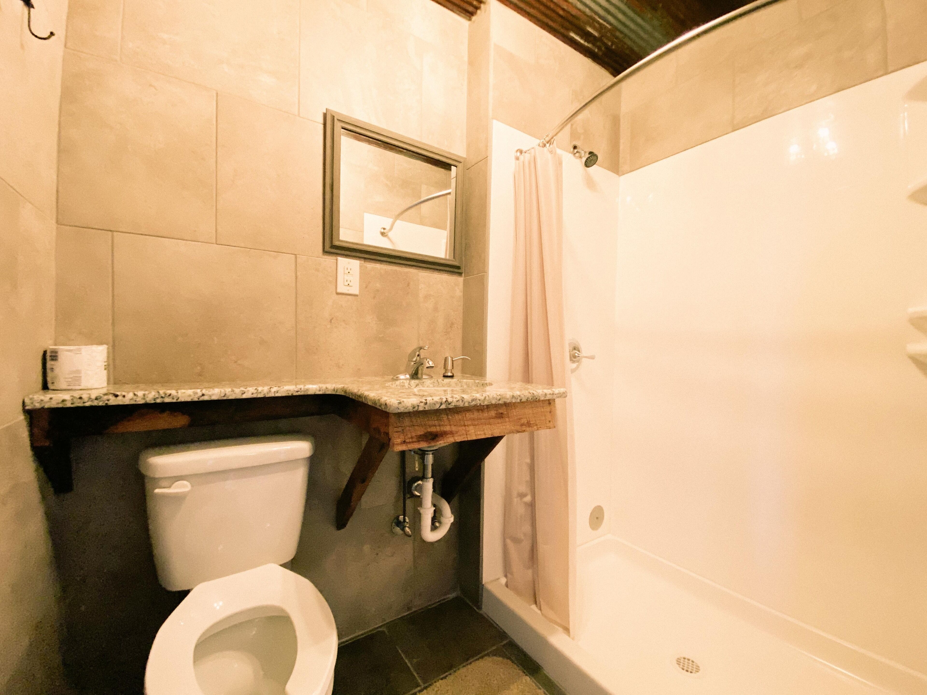 A bathroom with a toilet, sink, and shower.