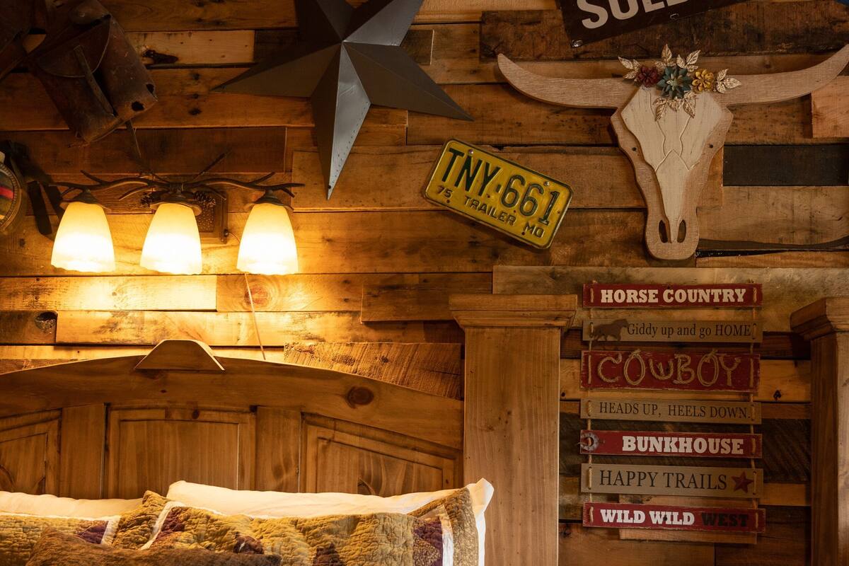A rustic room with a bed, wooden walls, a star decoration, a 'SOLD' sign, and a 'TNY 661' sign.
