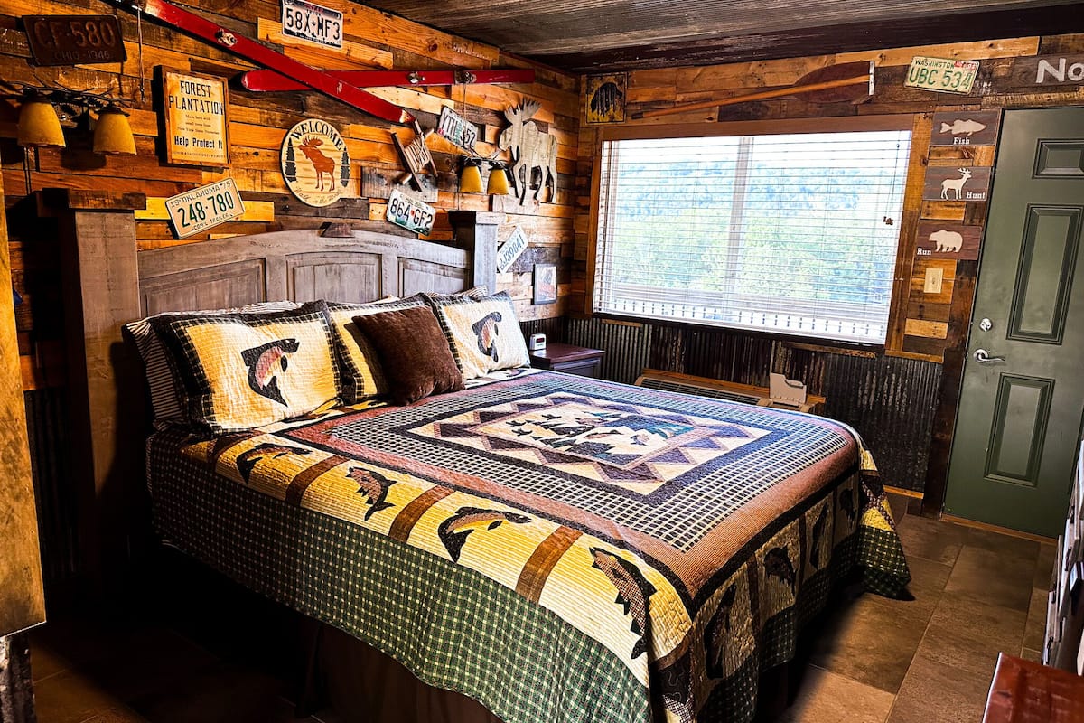 A rustic room with a large bed, wooden walls, and various signs and decorations.