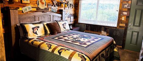 A rustic room with a large bed, wooden walls, and various signs and decorations.