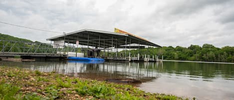 A large, open-air structure with a flat roof, surrounded by water and greenery.