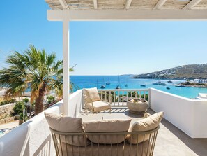 A balcony with a view of the sea, featuring a seating area with cushions and a small table. - MyMykonos Villa II Beach Front  (Mykonos)