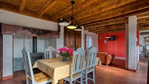 A dining area with a wooden ceiling, a red wall, and a tiled floor. - La Petite Ferme near DOMME8FP3Q6W9+8R 44.7958121,1.2195112 (Domme)