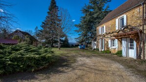 A rural road leading to a stone house with a tiled roof, surrounded by trees and a clear blue sky. - La Petite Ferme near DOMME8FP3Q6W9+8R 44.7958121,1.2195112 (Domme)