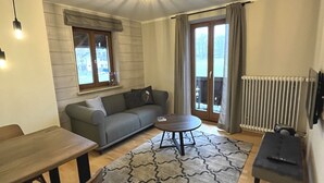 A living room with a sofa, a dining table, a coffee table, and a fireplace. - In the immediate vicinity of the lake, small, fine apartment newly renovated (Bad Wiessee)