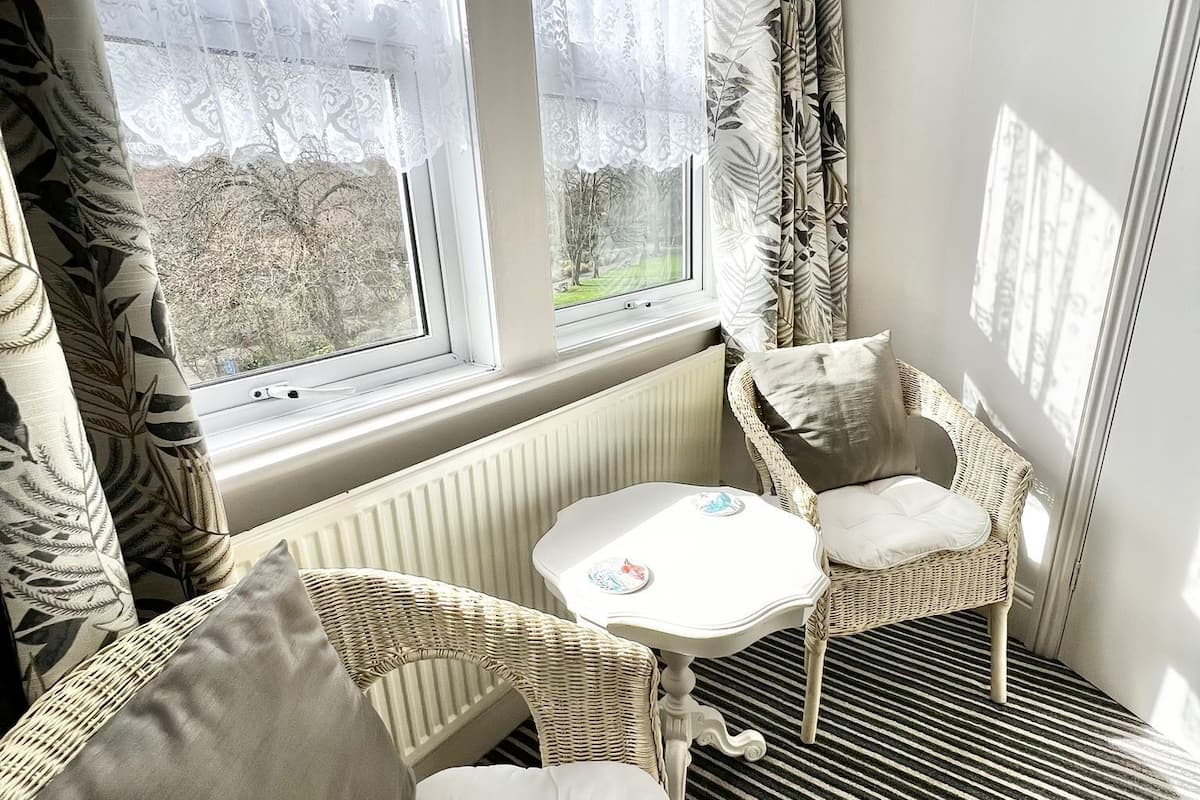 A cozy corner with a wicker chair, a cushioned sofa, and a small table with decorative plates.