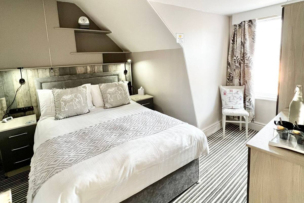 A modern hotel room with a large bed, a desk, and a chair.