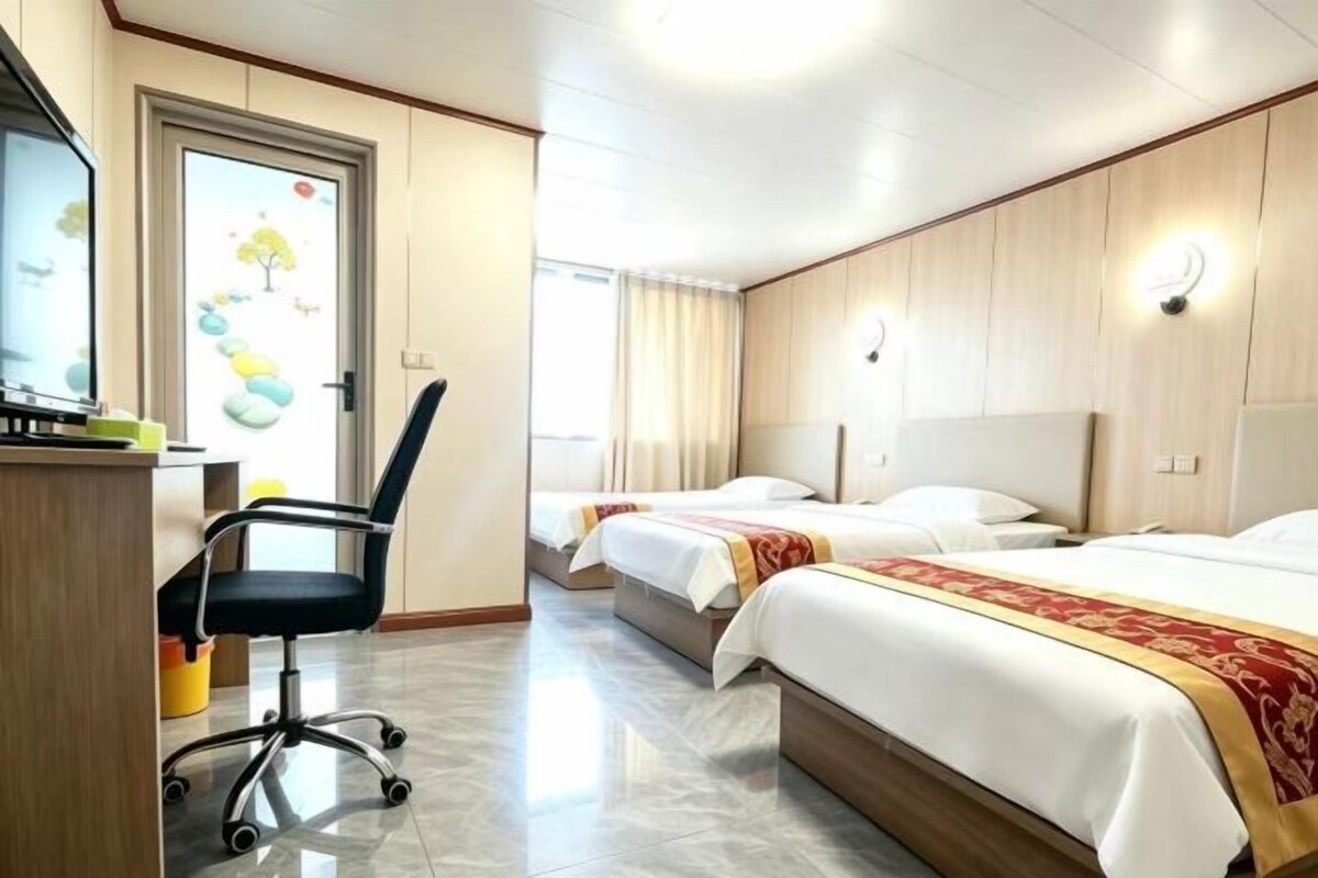 Une chambre d’hôtel équipée d’un bureau, de deux lits, d’une chaise et d’un téléviseur.