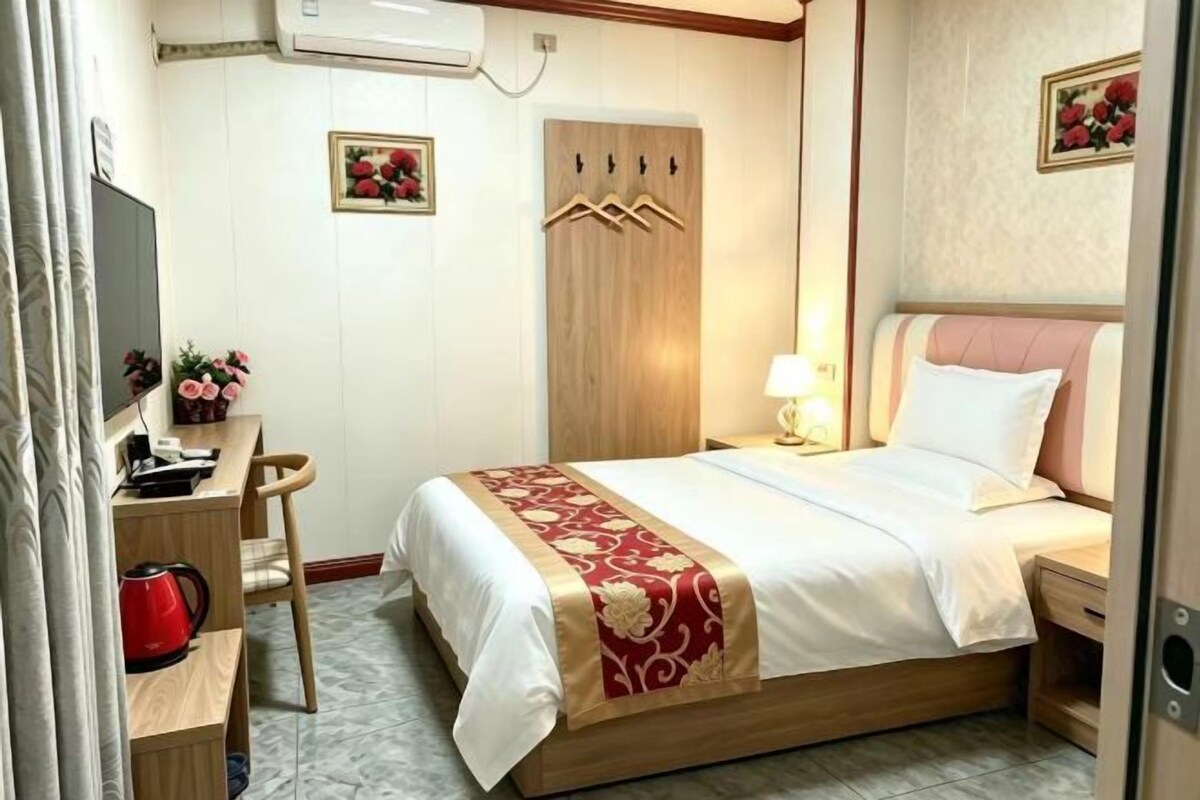 Une chambre d’hôtel comprenant un lit, une table de chevet, un bureau, une chaise et un téléviseur.