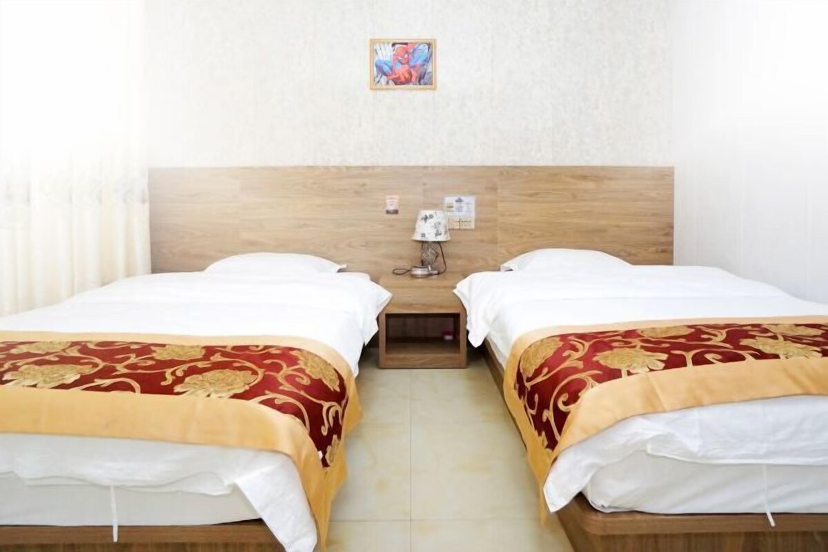 Una habitación de hotel con dos camas, un cabecero de madera, una mesita de noche y un cuadro colgado en la pared.