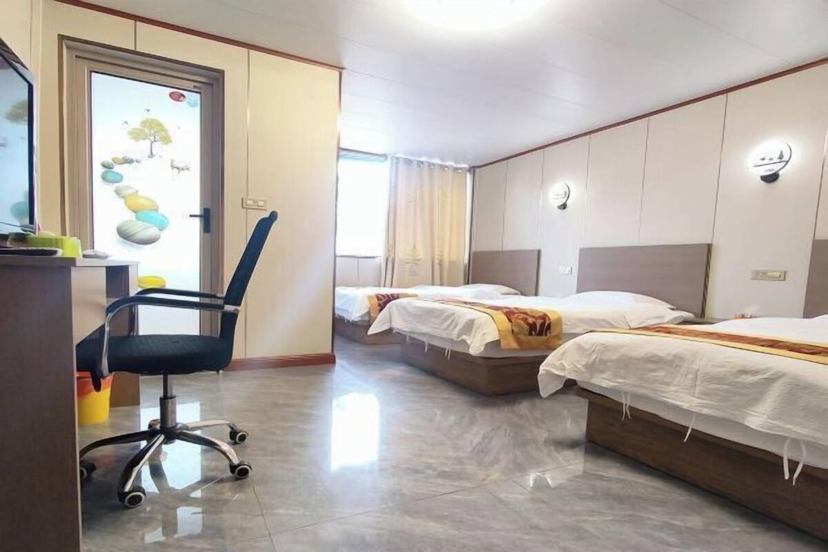 Habitación de hotel con dos camas, un escritorio con silla y una ventana con cortinas.