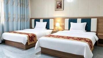 Une chambre d’hôtel avec deux lits, une table de chevet avec une lampe et un rideau.