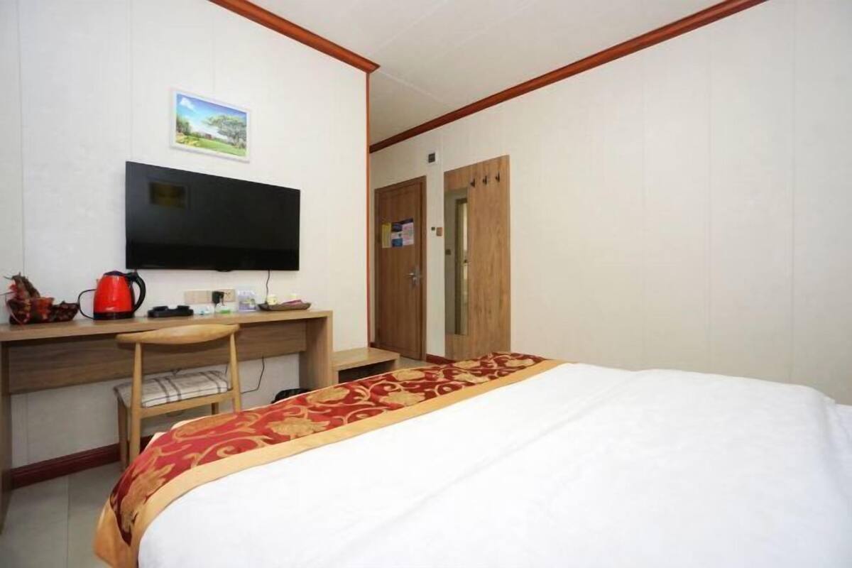 Una habitación de hotel con cama, escritorio con silla, televisor y armario.