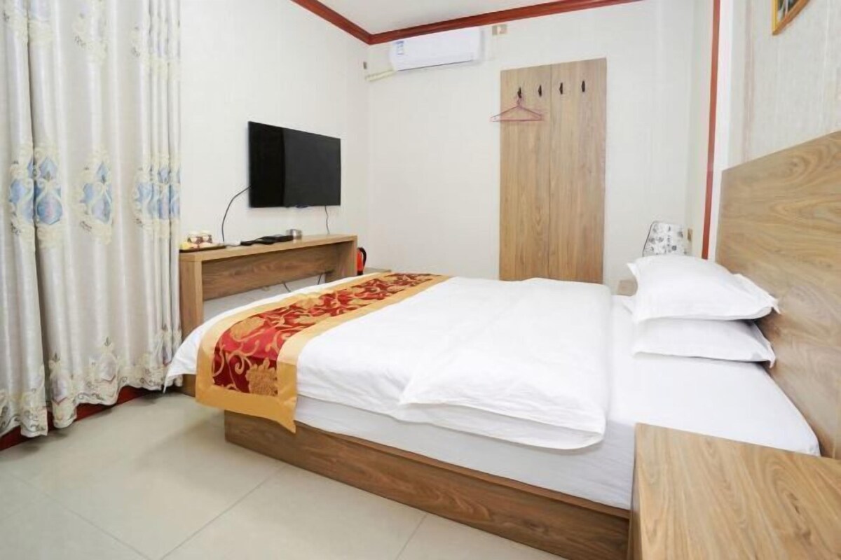 Un dormitorio con cama de madera, televisor en la pared y armario.