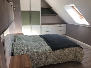 Ein Schlafzimmer mit Hochbett, eingebautem Kleiderschrank, Dachfenster und kleinem Fenster.