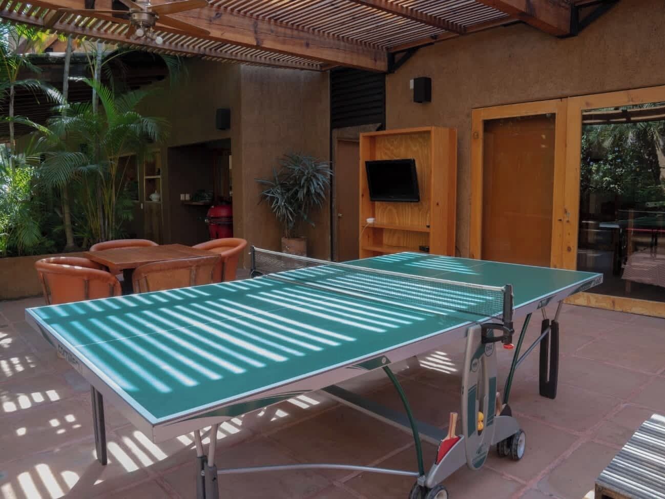 Un tavolo da ping pong in un'area esterna con sedie e una pianta in vaso.