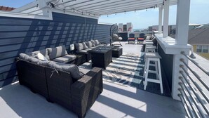A rooftop patio with outdoor seating, a pergola, and a view of the cityscape. - SeaRenity with rooftop and ocean views (Carolina Beach)