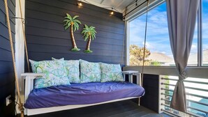 A bed with patterned pillows, a dark headboard, and a view of the outdoors. - SeaRenity with rooftop and ocean views (Carolina Beach)
