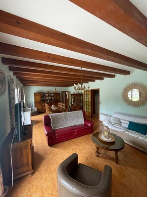 A living room with a red sofa, a white sofa, a wooden cabinet, and a chandelier.