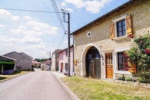 Una calle estrecha bordeada de edificios de piedra, algunos con arcos y contraventanas de madera.
