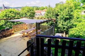 Un patio con mobiliario de madera y una pérgola.