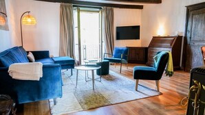 A living room with a blue sofa, a round coffee table, and a TV mounted on the wall.