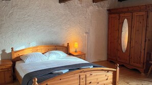 A wooden bed in a rustic room with a high ceiling and exposed beams.