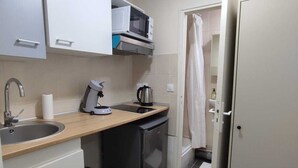A compact kitchen with a microwave, kettle, and sink. - RENT APPART - La Garenne Colombes (La Garenne-Colombes)