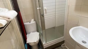 A small bathroom with a glass shower enclosure, a toilet, and a sink. - RENT APPART - La Garenne Colombes (La Garenne-Colombes)