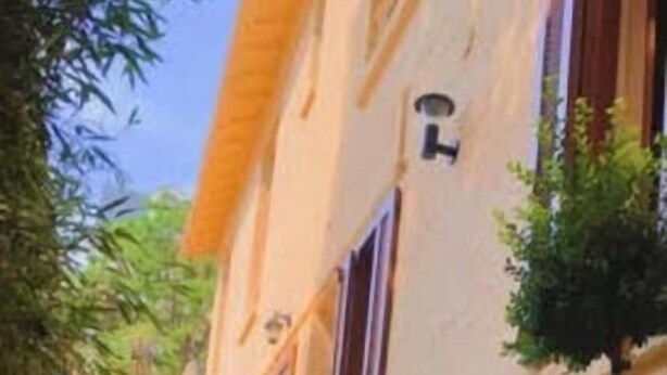 A narrow street with buildings on either side, potted plants, and a stone pavement. - RENT APPART - La Garenne Colombes (La Garenne-Colombes)