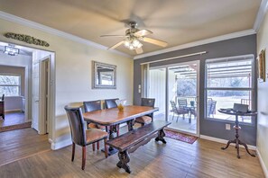 A dining area with a wooden table, chairs, and a bench. There is a ceiling fan, a window with blinds, and a door leading to another room. - Charming Palmer Family Home on 5 Acres! (Palmer)