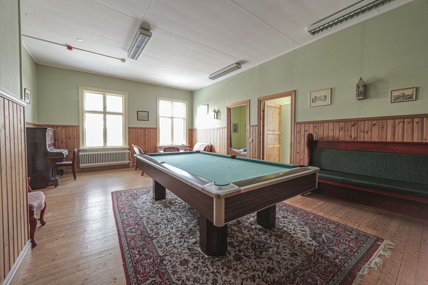 A pool room with a pool table, wooden benches, and a radiator.