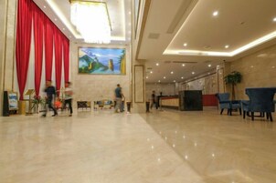 Un vestíbulo espacioso con un telón rojo de fondo, una recepción y una zona de estar con sillas.