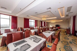 Un salón de conferencias de hotel con mesas, sillas y una pantalla grande.