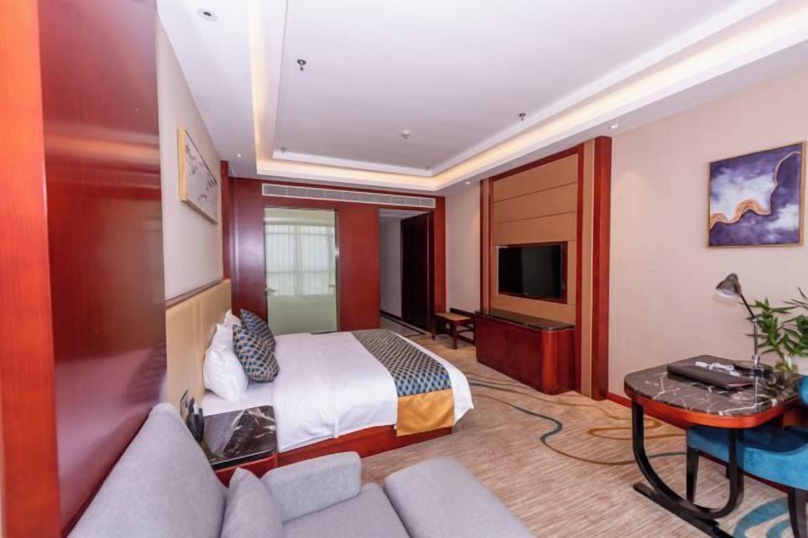 A hotel room with a bed, a desk, a TV, and a sofa.