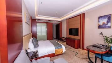 A hotel room with a bed, a desk, a TV, and a sofa.