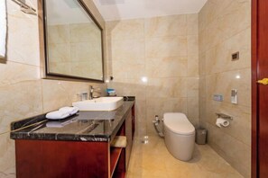 Une salle de bain avec un meuble-lavabo en marbre, des toilettes et un grand miroir.