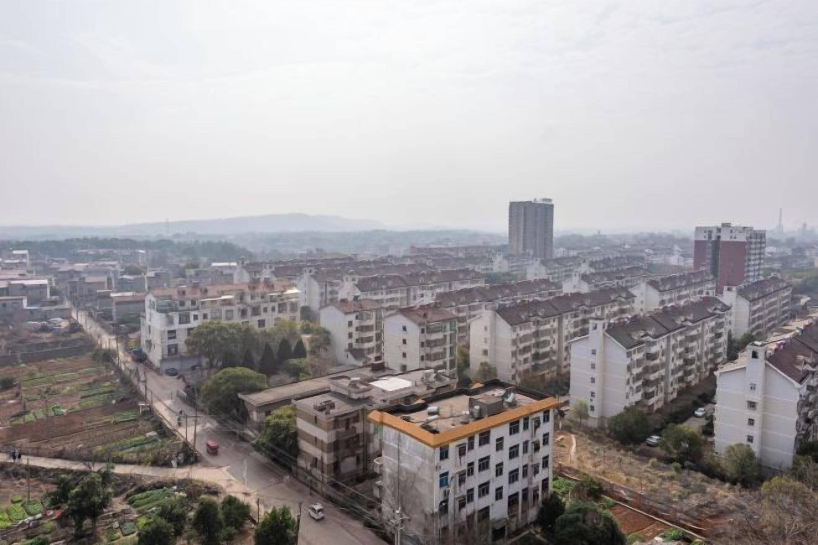 A cityscape with residential buildings, a prominent high-rise, and a road with vehicles.