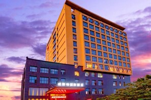Een meerhoog hotel met een opvallende ingang en veel ramen.