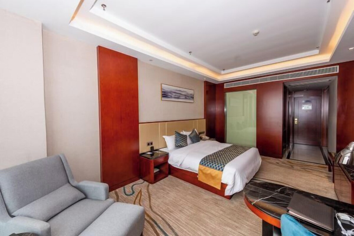Une chambre d’hôtel avec un lit, un bureau, une chaise, une table de chevet et une porte.