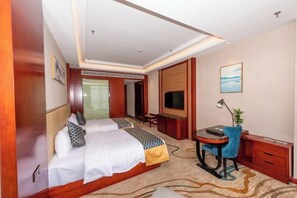 Une chambre d’hôtel avec deux lits, un bureau avec une chaise, une télévision et une petite table avec une lampe.