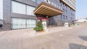 A building with a large entrance, a statue, and a signboard.