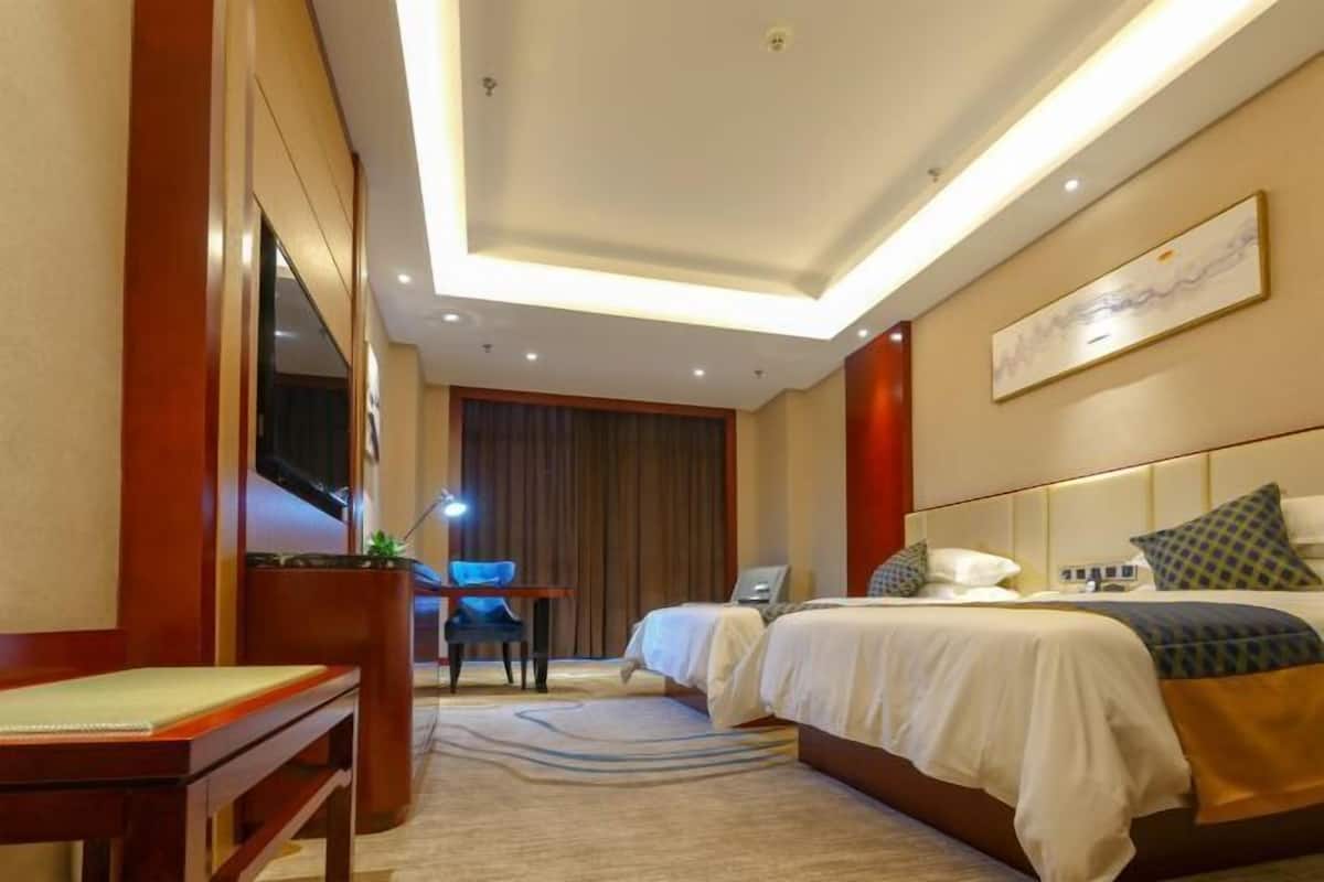 A hotel room with a bed, a desk, a chair, and a TV.