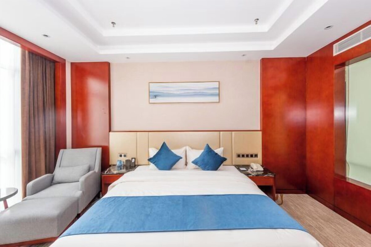 Une chambre d’hôtel avec un grand lit, un bureau, une chaise et un tableau au mur.