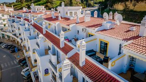 A row of white buildings with red-tiled roofs, balconies, and satellite dishes. - Sunny Duplex W/ Pool & Balcony by LovelyStay (Carvoeiro)