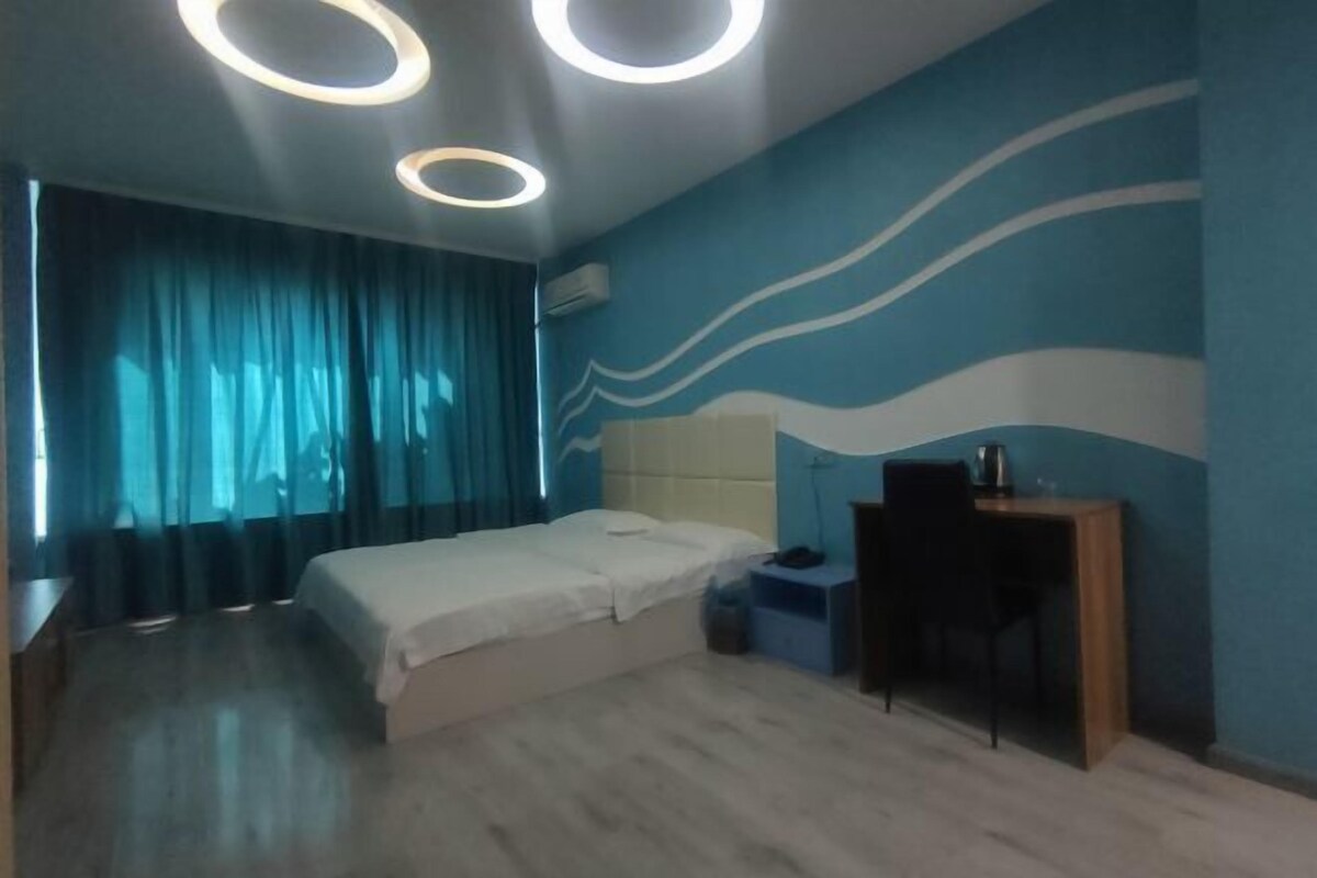 A bedroom with a bed, a desk, and a chair.
