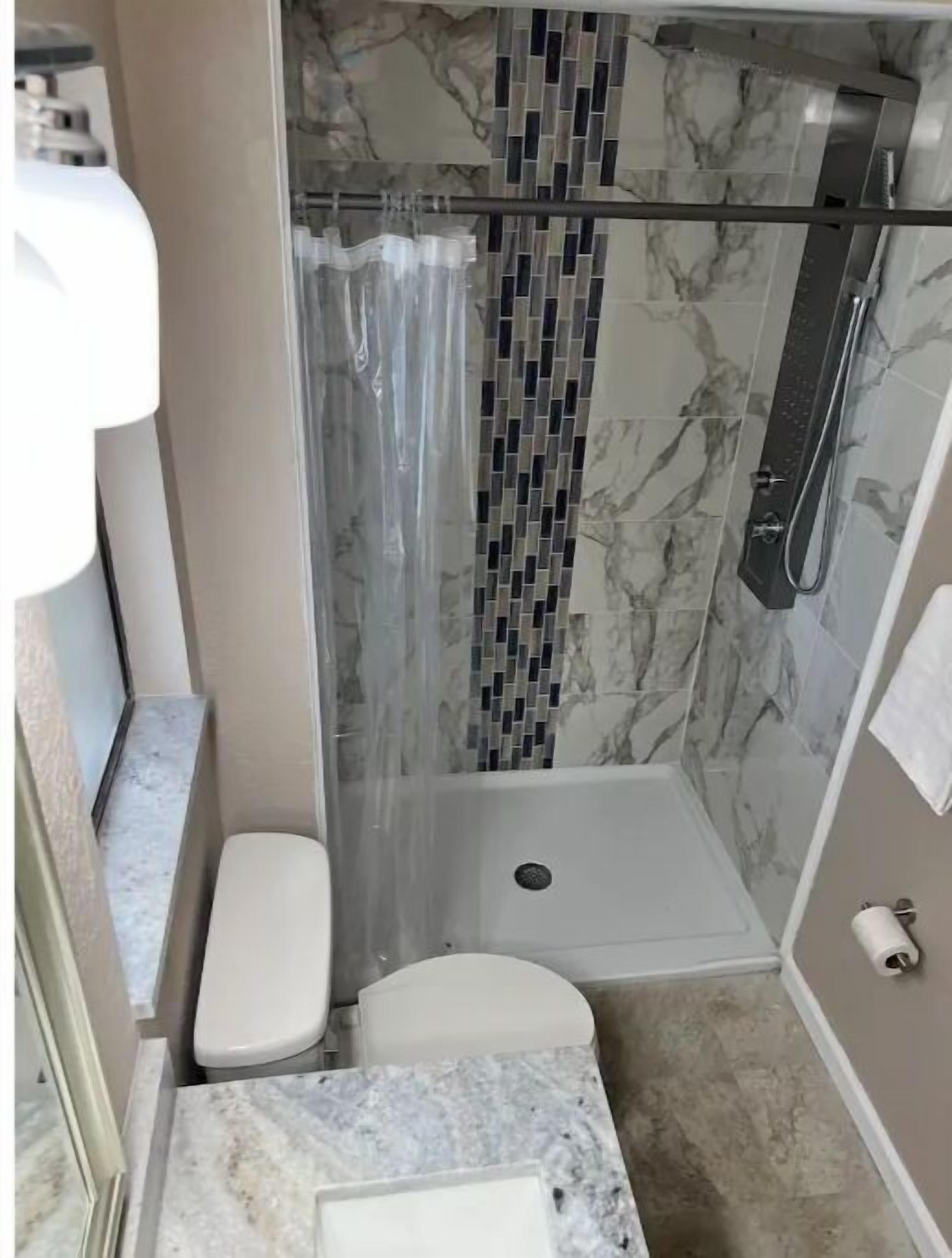 Een badkamer met douche, toilet en wastafel.