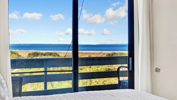 A room with a large window overlooking a beach and ocean. - 2-bedroom 2 bath condo at Lighthouse Point (Tybee Island)