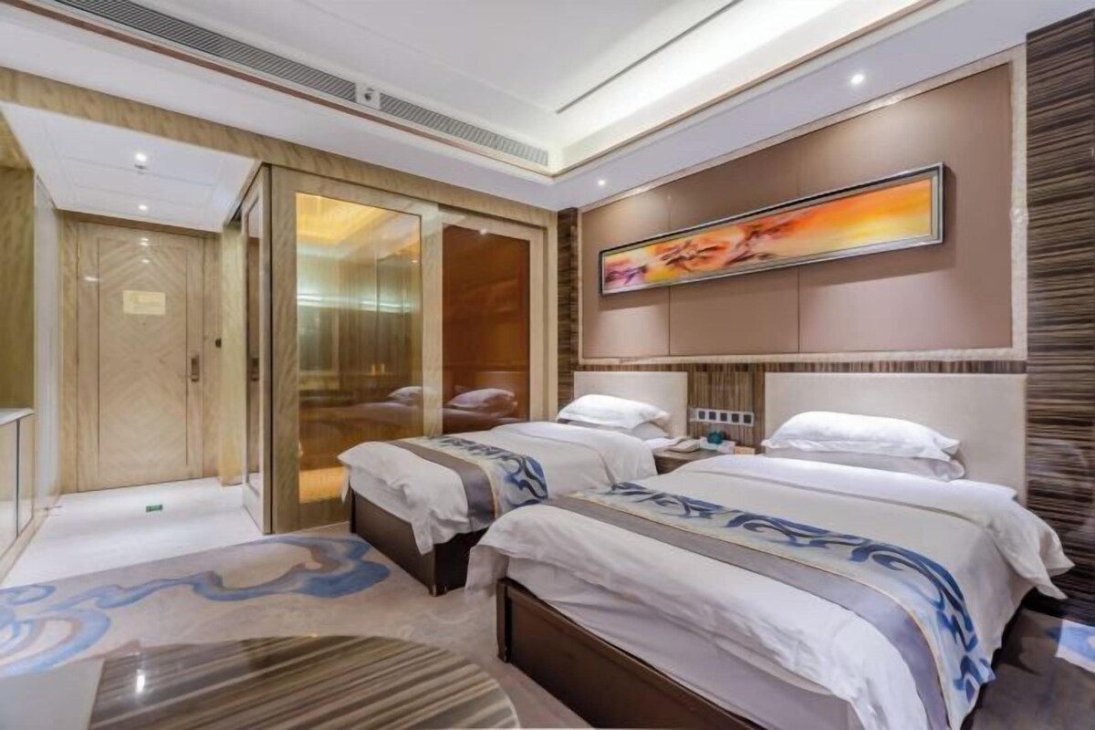 A hotel room with two beds, a large painting, a wardrobe, and a carpet with a swirl design.