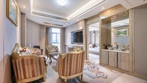 A spacious living area with a sofa, armchairs, a television, and a large mirror. - Xiliang Hotel (Wuwei)